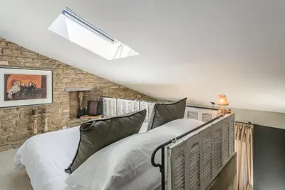 a bedroom with a bed and a stone wall at Domaine Les Roullets in Oppède