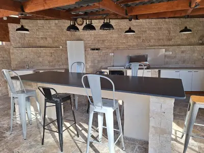 a kitchen with a large black counter and chairs at La Maison du Moulin de Tartay in Avignon