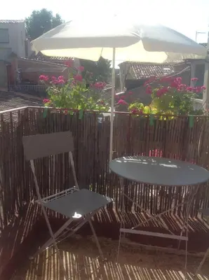 a table and a chair with an umbrella and flowers at Le petit Figuier in La Roque-dʼAnthéron