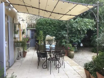 a patio with a table and chairs under an umbrella at Le petit Figuier in La Roque-dʼAnthéron