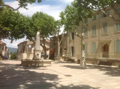 a statue in the middle of a street next to a building at Le petit Figuier in La Roque-dʼAnthéron