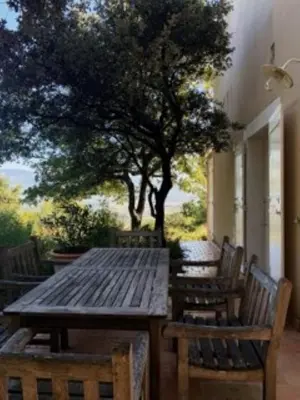 a wooden table and chairs on a patio with a tree at L'Hymette in Blauvac