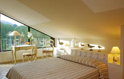 a bedroom with a bed and a desk and a window at Hotel du Poète in Fontaine-de-Vaucluse