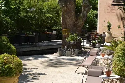 a patio with tables and chairs and a tree at Hotel du Poète in Fontaine-de-Vaucluse