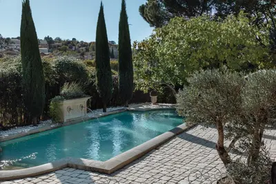 a swimming pool in a garden with trees and bushes at La Madone in Apt