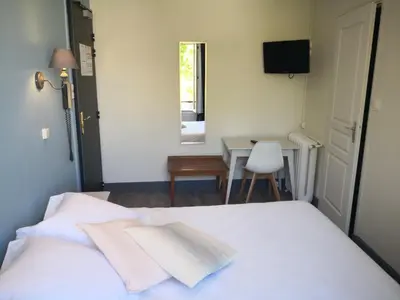 a bedroom with a white bed with a table and a television at Grand Hôtel De La Poste in Salon-de-Provence