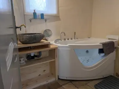 a bathroom with a large tub next to a sink at Les Rapieres Mireio in Gordes