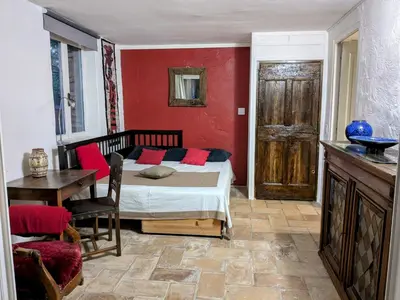 a bedroom with a bed with red walls and a table at Les Rapieres Mireio in Gordes