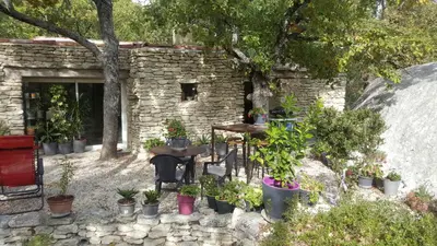 a stone building with tables and potted plants at Les Rapieres Mireio in Gordes