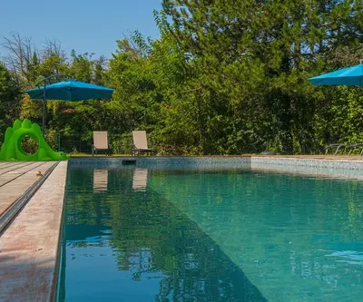 a swimming pool with two chairs and an umbrella at Le Cabanon in Le Thor