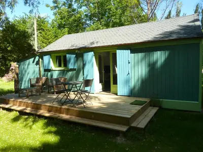 a house with a deck with chairs and a table at Le Cabanon in Le Thor