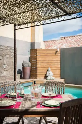 a table with glasses and plates on a patio at Un Ryad a l'Isle in LʼIsle-sur-la-Sorgue