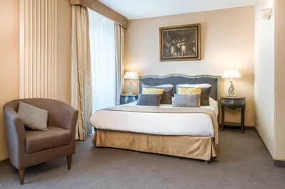 a bedroom with a king sized bed and a chair at Hôtel des Augustins in Aix-en-Provence