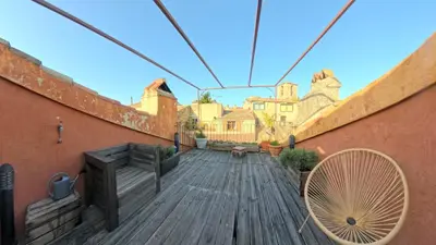 a wooden deck with a chair and some buildings at Le 47 - Rentals in South of France in Beaumont-de-Pertuis