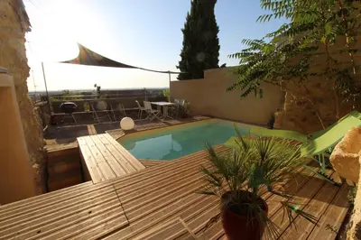 a swimming pool with a wooden deck and a table at The Panoramic House in Lagnes