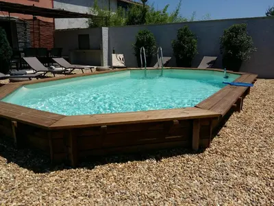 a large swimming pool with a wooden deck and sidx sidx sidx sidx at Un Coin de Provence in LʼIsle-sur-la-Sorgue