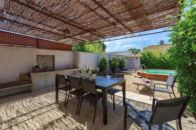 a patio with a table and chairs and a pool at Un Coin de Provence in LʼIsle-sur-la-Sorgue
