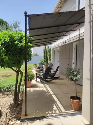 a patio with awning and a table and chairs at Un Coin de Provence in LʼIsle-sur-la-Sorgue