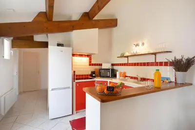 a kitchen with a white refrigerator and red cabinets at Mas et Gite de la Picholine in LʼIsle-sur-la-Sorgue