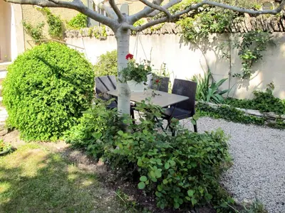 a table and chairs under a tree in a garden at Holiday Home Le Cèdre by Interhome in Ménerbes