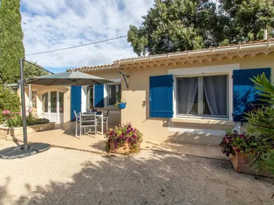 a house with blue shutters and a patio at Holiday Home Les Amandiers by Interhome in Mazan