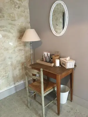 a table with a chair and a lamp and a mirror at La Bastide des Songes - Demeure d'hôtes in Robion en Luberon