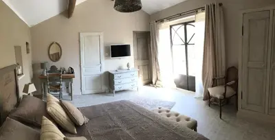 a bedroom with a bed and a tv and a window at La Bastide des Songes - Demeure d'hôtes in Robion en Luberon