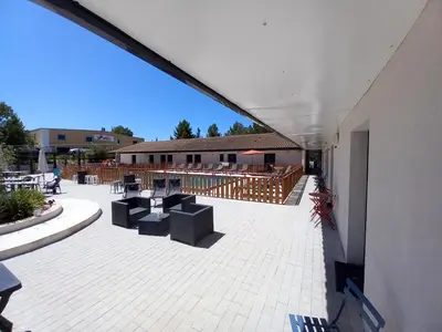 a patio with chairs and tables and a building at Le Clos la Verdière in Velaux