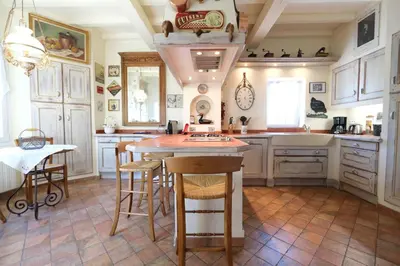 a kitchen with white cabinets and a table and chairs at Semi-detached provencal farm with swimming pool in Orgon
