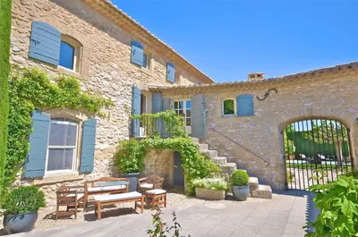 a brick building with benches and a patio at Ferme St Roch in Robion en Luberon