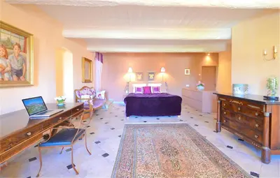 a bedroom with a bed and a desk with a laptop at Ferme St Roch in Robion en Luberon