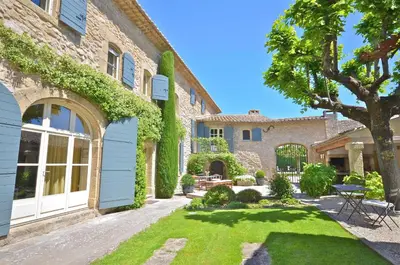 an exterior view of a house with a yard at Ferme St Roch in Robion en Luberon