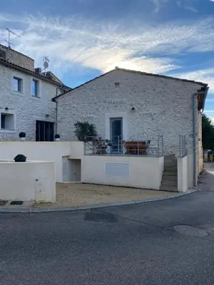 a white brick building with a gate and a balcony at Au bon logis Luberon 50m2 in Cheval-Blanc