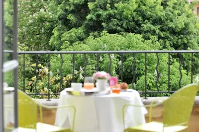 a table with a white table cloth and flowers on a balcony at La Maison d'Aix 1785 - Hôtel Particulier & Spa in Aix-en-Provence