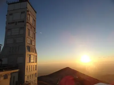 a tall building with the sunset in the background at La belle histoire Gîte Montmirail in Bédoin