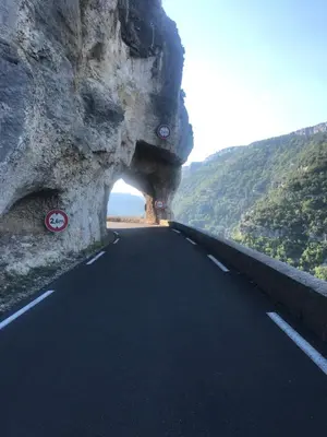 a road with a cave in the side of a mountain at La belle histoire Gîte Montmirail in Bédoin