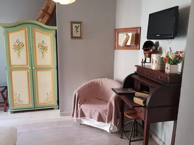 a room with a chair and a desk and a television at Le Crillon in Murs
