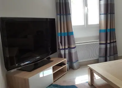 a living room with a flat screen television on a cabinet at Mas des Mûriers in Saumane-de-Vaucluse