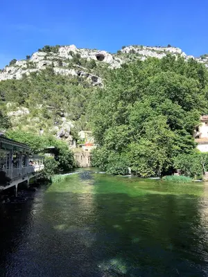 a river with green water and a mountain in the background at Séjour Authentique et provençal in Fontaine-de-Vaucluse