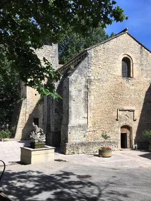 an old brick church with a statue in front of it at Séjour Authentique et provençal in Fontaine-de-Vaucluse