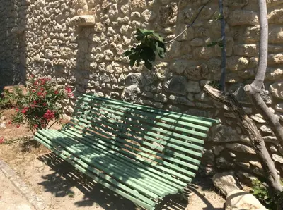 a green bench in front of a stone wall at Maison Daumas Billard Français et Piscine in Robion en Luberon