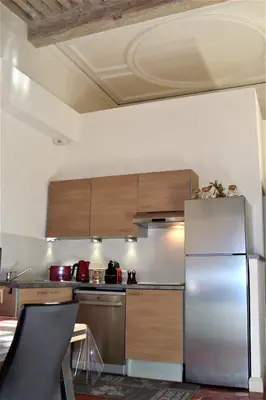 a kitchen with a stainless steel refrigerator and wooden cabinets at Appartement de caractère entre St Rémy et Avignon, 74m2, 2 à 4 personnes in Noves
