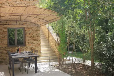 a table and chairs under an umbrella on a patio at La Caprine in Gordes