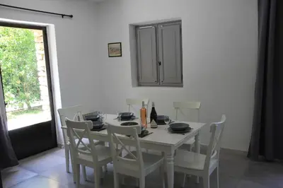 a white dining room table with white chairs and a window at La Caprine in Gordes