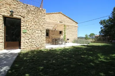 a brick building with a door in a yard at La Caprine in Gordes