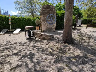 a brick fireplace next to a tree in a park at Villa Les Carlets in Saignon