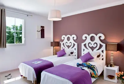 two beds in a room with purple and white at Lagrange Vacances - Le Clos Savornin in Saint-Saturnin-les-Apt