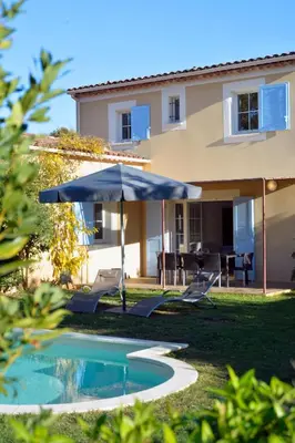 a pool with an umbrella and chairs and a house at Lagrange Vacances - Le Clos Savornin in Saint-Saturnin-les-Apt