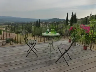 a patio with a table and chairs on a deck at Maison Itzé in Saint-Saturnin-les-Apt