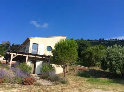a house on a hill with a balcony and trees at Maison Itzé in Saint-Saturnin-les-Apt